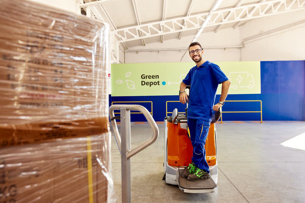 Man driving electric pallet jack in green depot